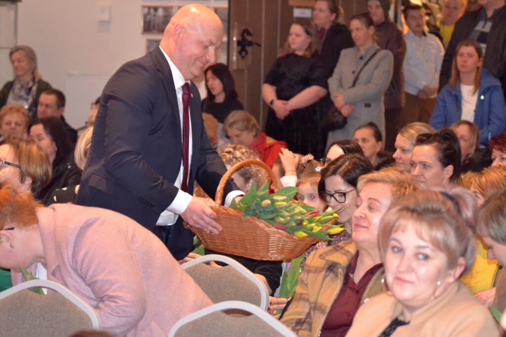 Dzień Kobiet, Szydłów, 8 marca 2023. Burmistrz rozdaje kwiaty obecnym Paniom.