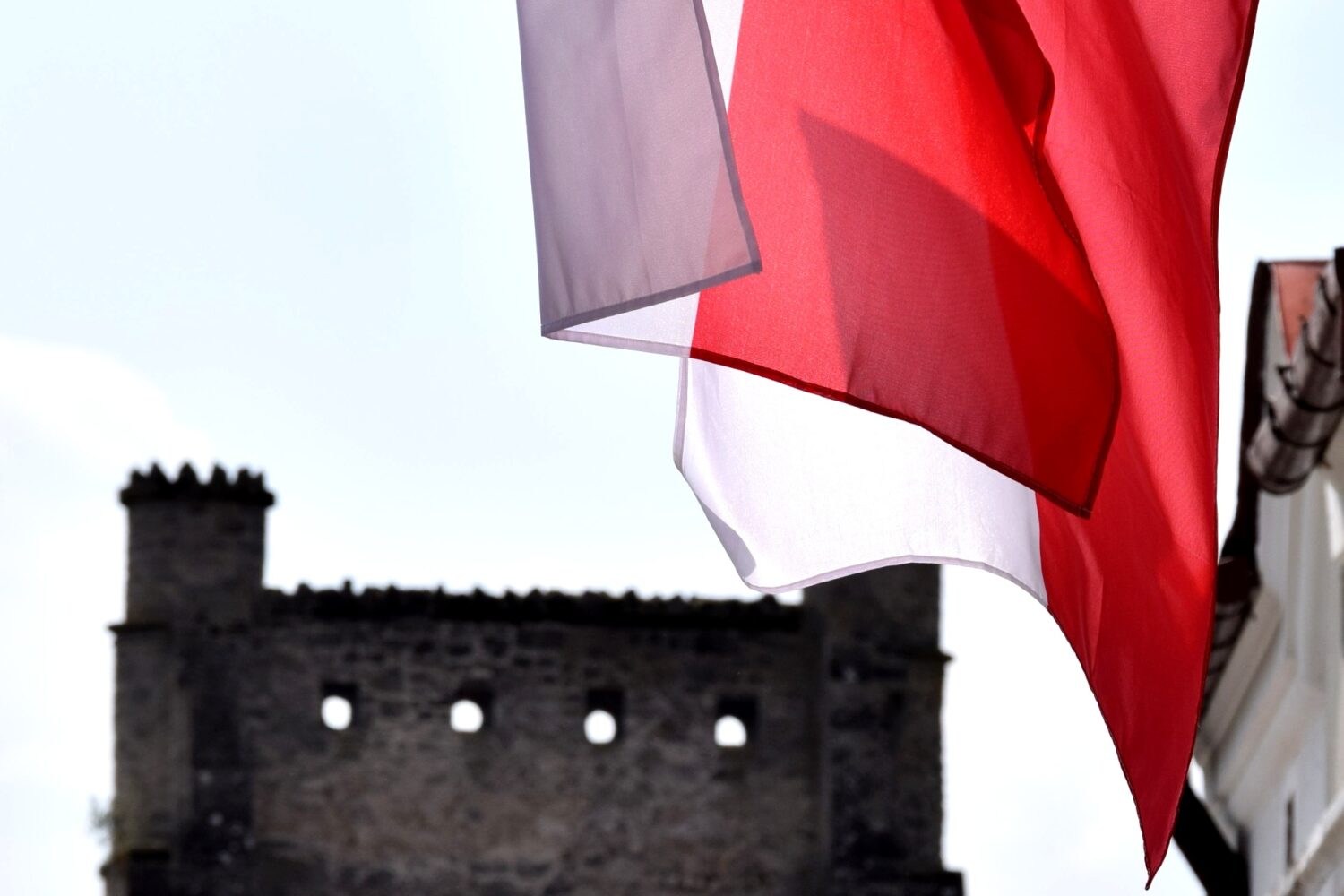 Flagi biało-czerwone i zwieńczenie Bramy Krakowskiej.
